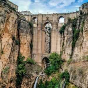 Un puente muy grande suspendido entre dos grandes acantilados y muy cerca encuentra viviendas de la población. El lugar déjà una vista en profundidad con los acantilados llenos de vegetación, así que abajo de sus acantilados vemos cascadas de agua