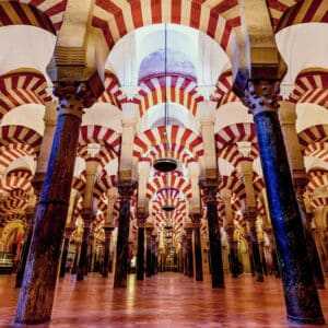 Habitación muy grande en profundidad, llena de pilares y un techo con molduras arqueadas, coloreado en rayas blancas y rojas que dan un efecto óptico visual
