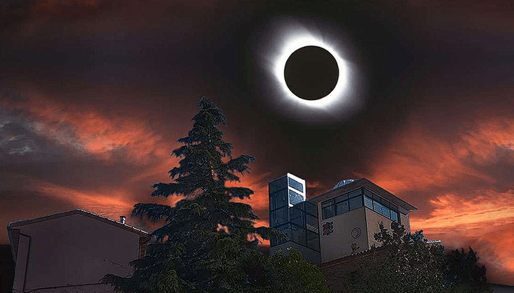 Imagen artística de un eclipse solar total en un cielo dramático con nubes teñidas de rojo y naranja por el atardecer. El sol aparece como un disco negro rodeado por una corona de luz blanca brillante. En la parte inferior, se ven las siluetas de edificios modernos y un pino oscuro que contrastan con el cielo iluminado.
