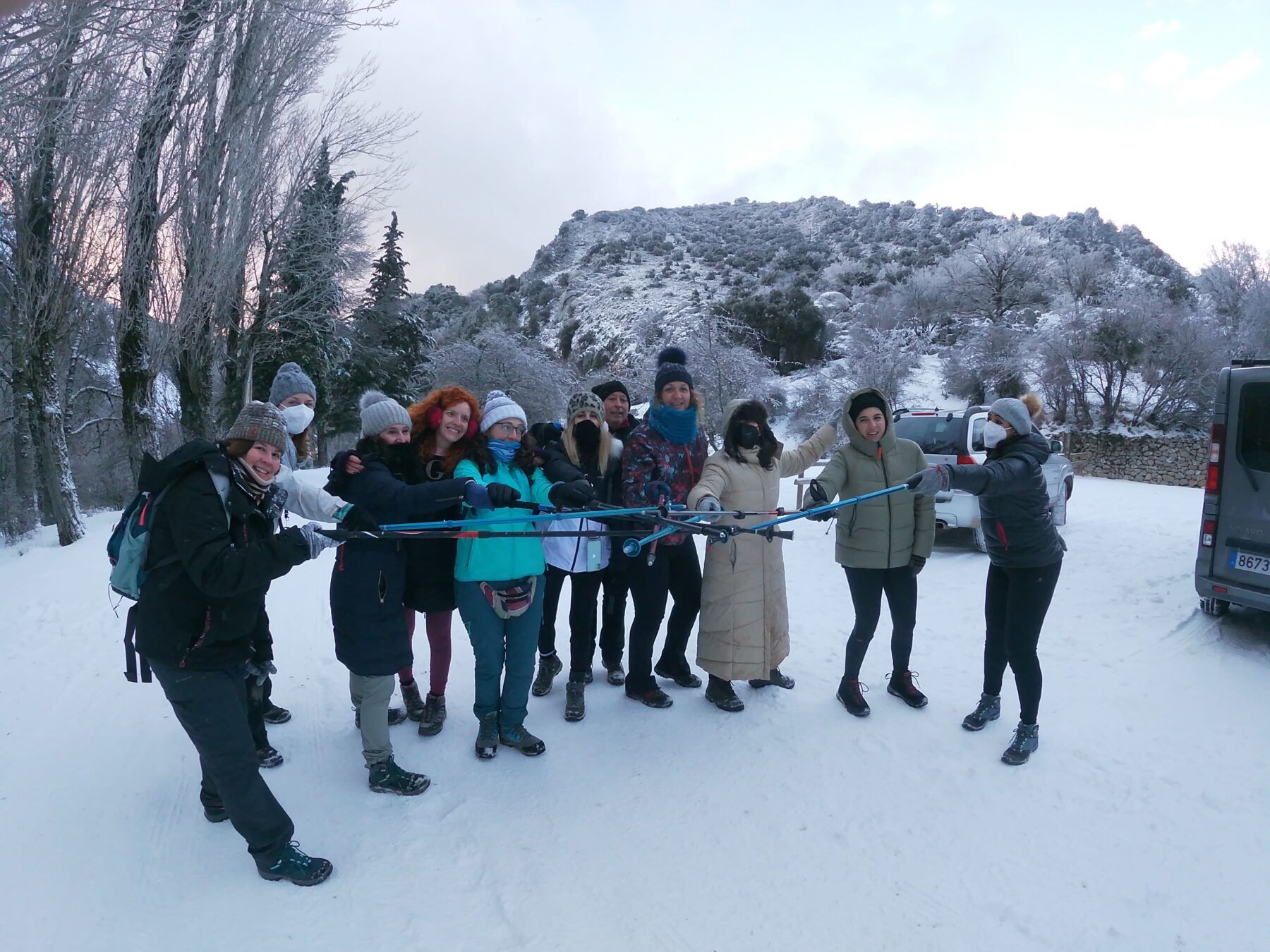Otro ángulo del mismo momento mágico en la nieve, con el grupo sonriente sujetando bastones y las colinas nevadas de la Sierra de Cazorla como telón de fondo invernal.