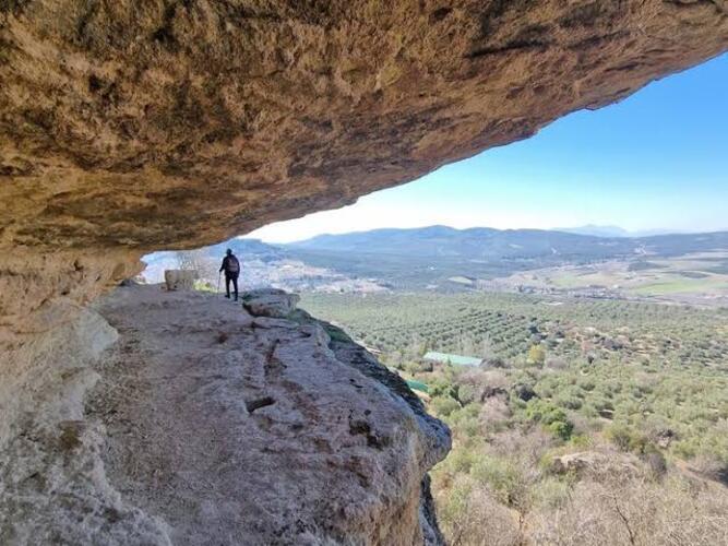 Mirador natural bajo una roca con vistas a valles y olivares de Andalucía.